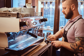 Side view of a barista cleans the portafilter before preparing the cappuccino in a coffee shop or restaurant.