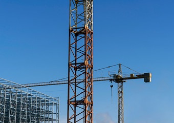 Construction cranes with a clear sky behind.