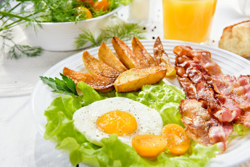 Bacon and potatoes. Fried bacon with French fries and tender egg, and a glass of fresh juice.