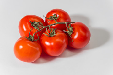 red tomatoes on a twig on a white background