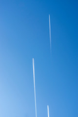 Blick nach oben in den strahlend blauen und wolkenlosen Himmel mit 3 Flugzeugen mit Kondensstreifen die parallel und versetzt in die gleiche Richtung fliegen
