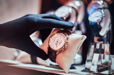 Close-up of the seller's hand in gloves shows the exclusive men's watch from the new collection in...