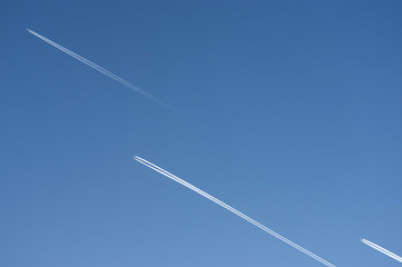 Blick nach oben in den strahlend blauen und wolkenlosen Himmel mit 3 Flugzeugen mit Kondensstreifen...