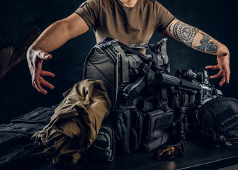 Casually dressed man showing his military uniform and equipment. Modern special forces equipment....