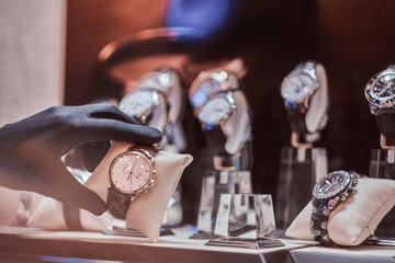 Close-up of the seller's hand in gloves shows the exclusive men's watch from the new collection in...