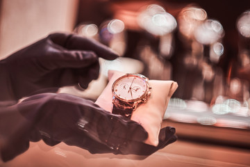 Close-up of the seller's hands in gloves shows the exclusive men's watch from the new collection in...