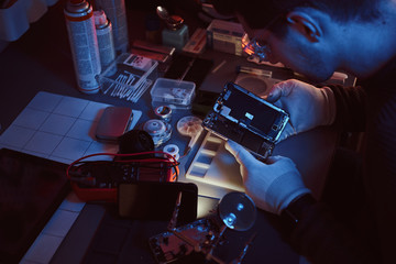 The technician carefully examines the integrity of the internal elements of the smartphone in a...