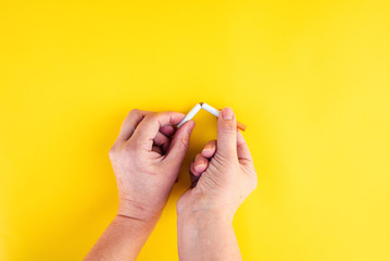  Female hands breaking a cigarette in half on isolated background. quit smoking concept