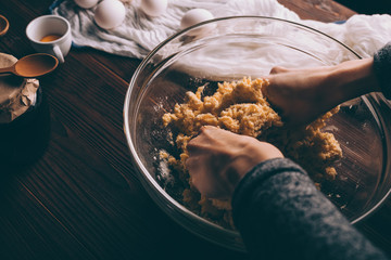Top view of female hands kneading dough in bowl