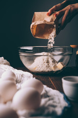 Woman's hands pouring flour into bowl