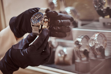 Close-up of the seller's hands in gloves shows the exclusive men's watch from the new collection in...