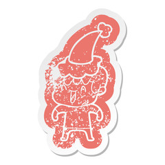 cartoon distressed sticker of a laughing boy wearing santa hat