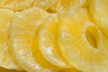 Dried pineapple candy rings, in powdered sugar, close-up in sunlight.