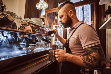 Handsome barista in uniform preparing a cup of coffee for a customer in the coffee shop