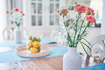 Flowers in a white ceramic vase standing on dinner table