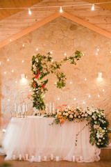 Coziness and style. Modern event design. Table setting at wedding reception. Floral compositions with beautiful flowers and greenery, candles, laying and plates on decorated table.