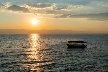Fototapeta na wymiar Sunrise over the sea, view of the drifting boat.