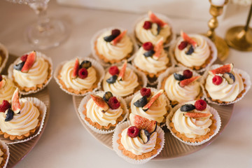 Candy bar with tasty desserts and appetizers at wedding reception. Decorated with flower compositions and candles. Sweet food, dessert, buffet, catering table, restaurant.
