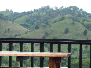 Wooden table with about bench outdoors, green hills background.