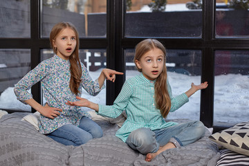 The cute little girl is snitching at her sister, pointing at her with her finger