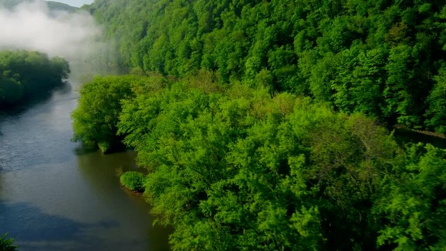 Aerial flyover view of islands in river near forest approaching fog / Susquehanna, Pennsylvania, United States