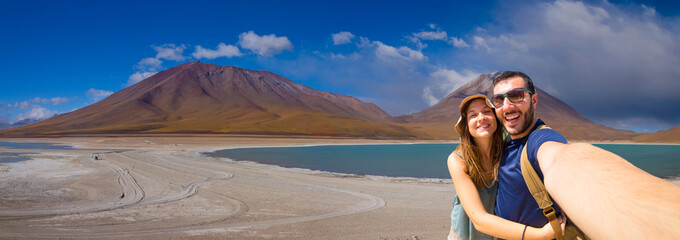 Happy couple tourists backpacker taking selfie in Laguna Verde, the salt lake at the foot of the...