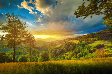 Colorful sunset over the green hills landscape