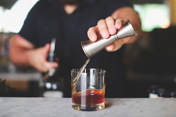 bartender pouring alcohol in a glass at a bar