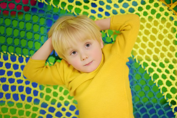 Fototapeta na wymiar Happy little boy having fun in amusement in play center. Child playing on indoor playground.