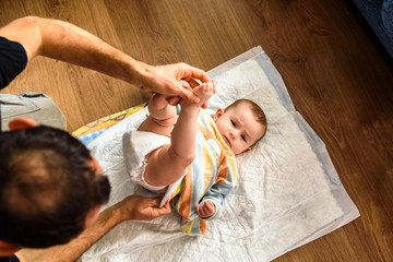 Father changing his daughter's dirty diaper.