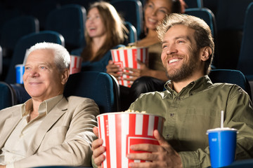 Senior man enjoying movies with his mature son together at the cinema