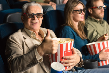 Senior man enjoying movies with his mature son together at the cinema