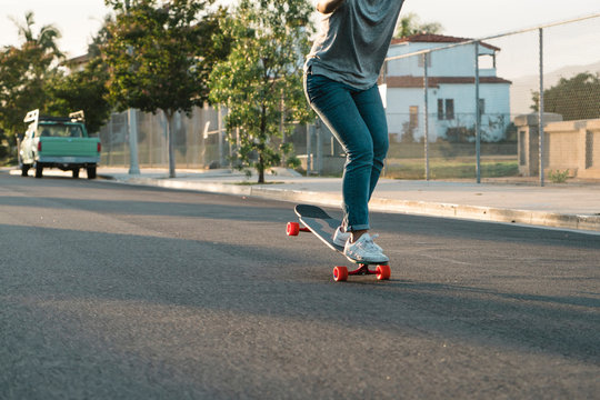 Low section of woman skateboarding on road against fence