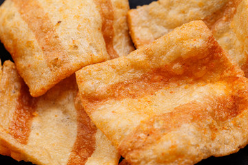 Chips salty bacon snack closeup details background. On black background. Close up.