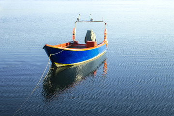 Small blue boat at the middle of the blue water