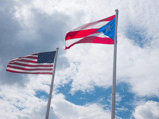 USA and Puerto Rico flags on a cloudy sky