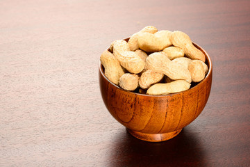 Peanuts. Dry nuts in bamboo bowl on the brown wooden table.