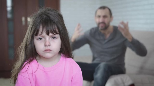 Portrait of a child in depression. The father screams at the sad little daughter.