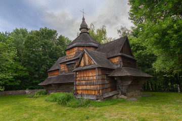 Fototapeta na wymiar Old wooden church among dense foliage in the open-air museum Pirogovo Kiev