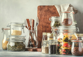 Stocks or set of cereals, pasta, groats, organic legumes and useful seeds in glass jars. Vegan source of protein and energy resources. Healthy vegetarian food. Domestic life scene.  - obrazy, fototapety, plakaty