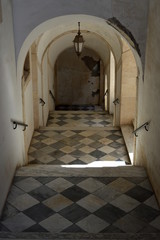 Fototapeta premium Old staircase with arched ceiling and chess tiled floor, Catania, Sicily, Italy