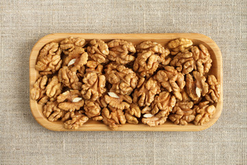 Big peeled walnuts in bamboo plate on rough linen cloth