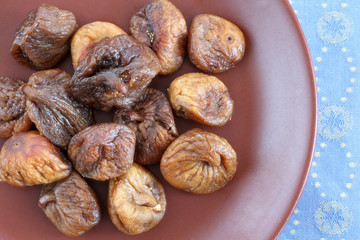 Dried figs on a brown ceramic plate on blue tablecloth