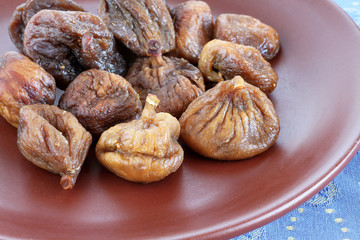 Dried figs on a brown ceramic plate on blue tablecloth