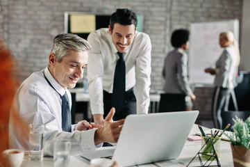 Happy businessmen working together on the computer in modern office.