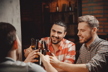Friends of men drink beer in dark bottles on bar pub, check. Friendship concept