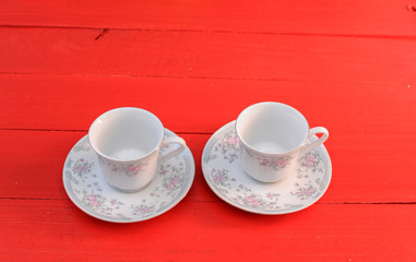 Empty white coffe cups with flower design on red wooden table. Two coffe cups