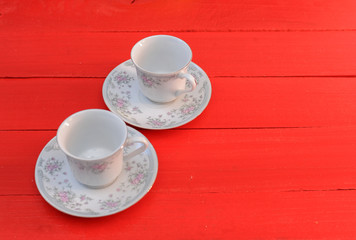 Fototapeta na wymiar Empty white coffe cups with flower design on red wooden table. Two coffe cups