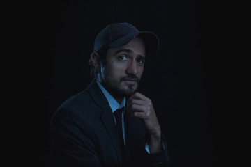 portrait with black background of a young man with cap and shirt and tie