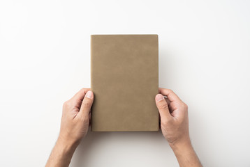 man hand hold brown notebook on white background